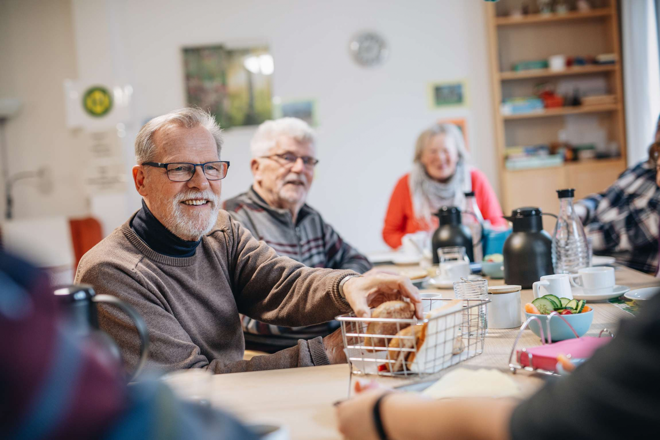 Älterer Herr greift beim Essen in den Brotkorb